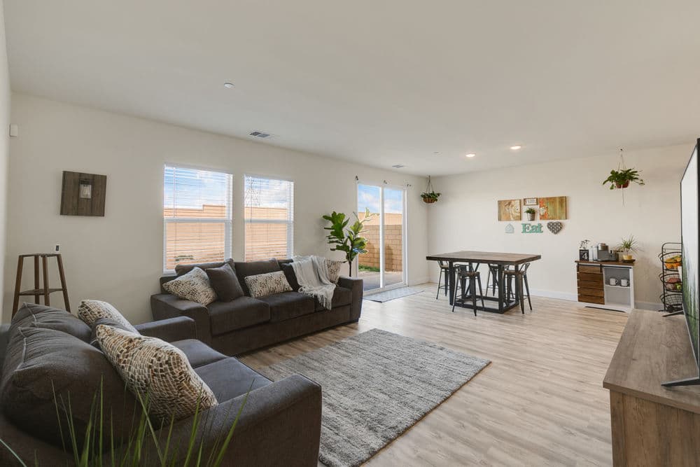 Modern living room with gray sofa, dining table, large windows, and stylish decor.