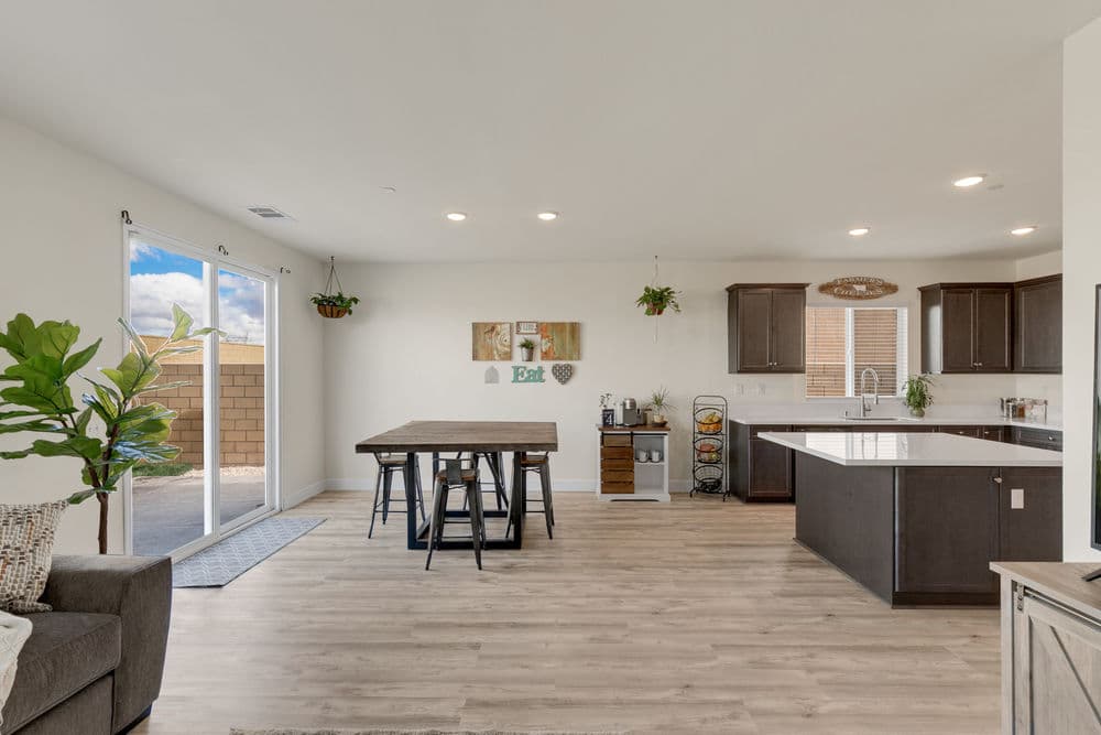 Modern open-concept kitchen and dining area with wooden table and bright natural light.