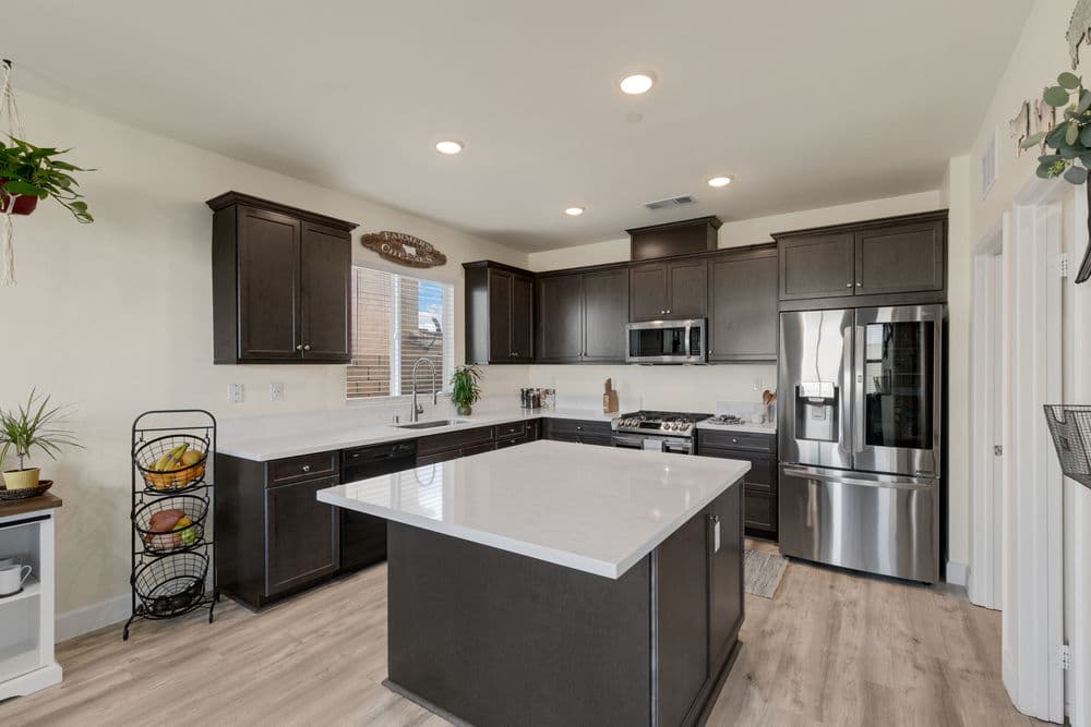 Modern kitchen with dark wood cabinets, stainless steel appliances, and a large island.