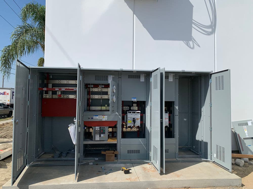 Electrical service panel with open doors, showcasing circuit breakers and wiring connections.