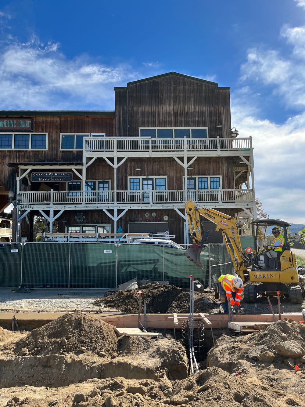 Construction scene at a rustic building with workers and machinery in Marin County.