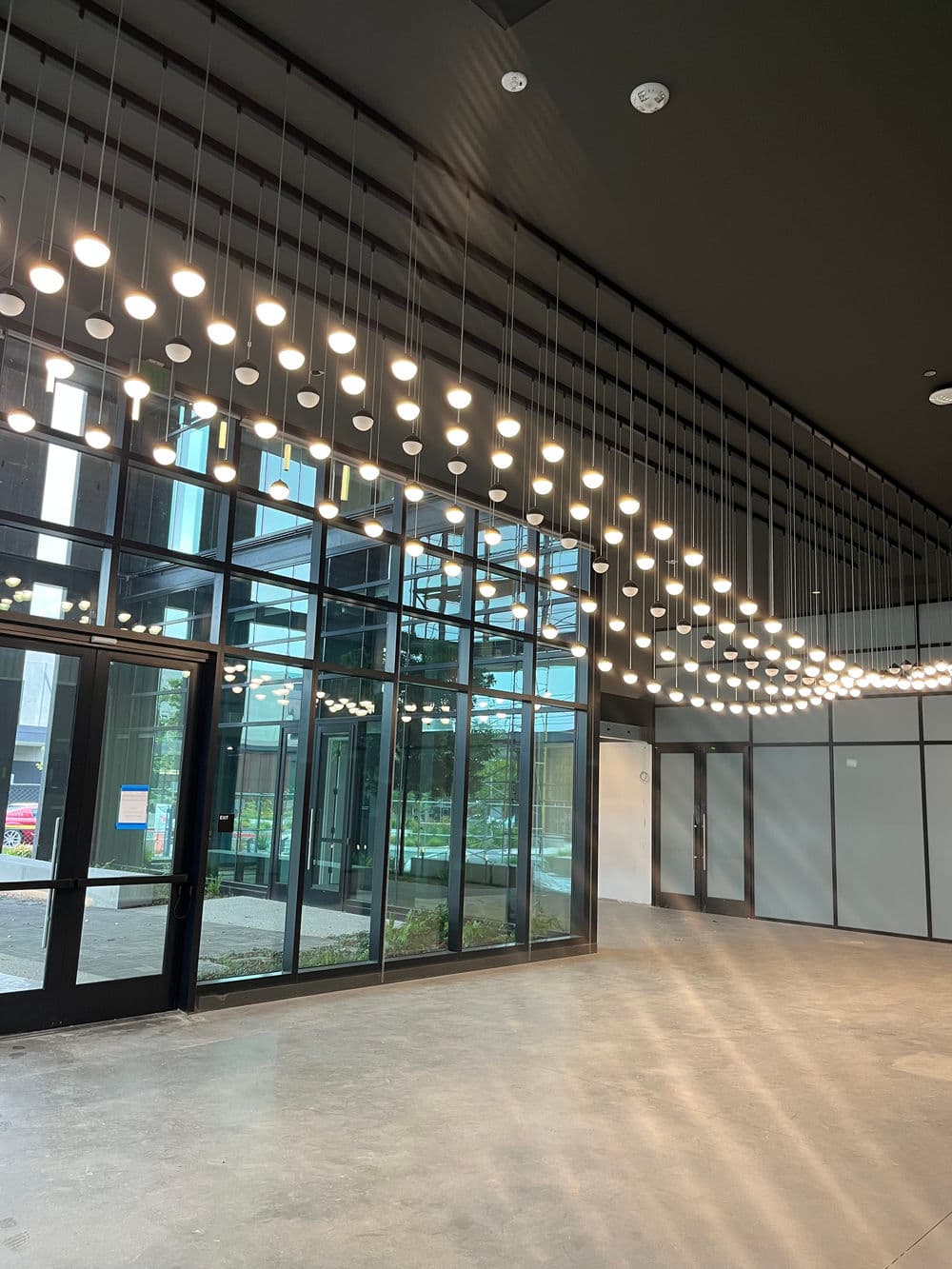 Modern interior design featuring hanging lights and large glass windows. Bright and spacious ambiance.