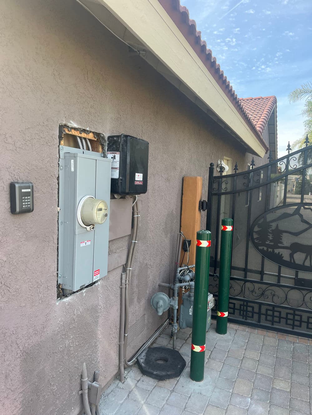 Exterior wall with electrical panel installation and gate access, featuring utility connections.