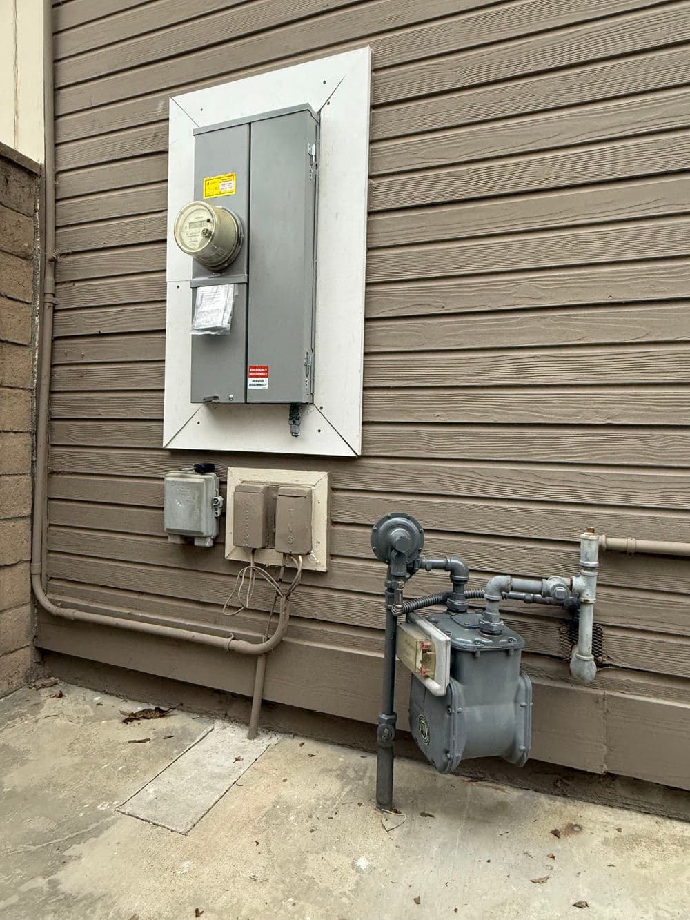 Gas meter and electrical service panel mounted on a building's exterior wall.