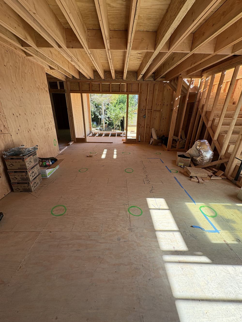 Interior view of a wooden structure under construction, showcasing framed walls and natural light.