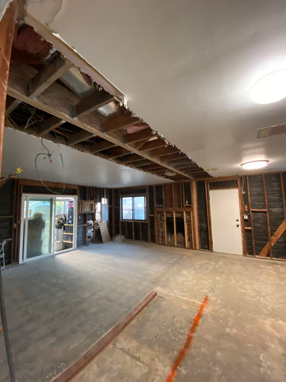 Renovated interior showcasing an open living space with exposed beams and unfinished flooring.