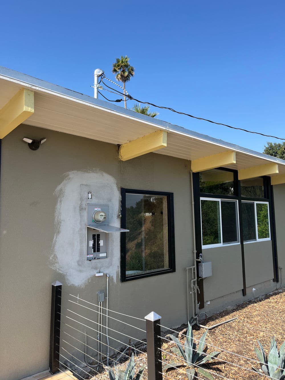 Modern home exterior with exposed utility box and clear blue sky in background.