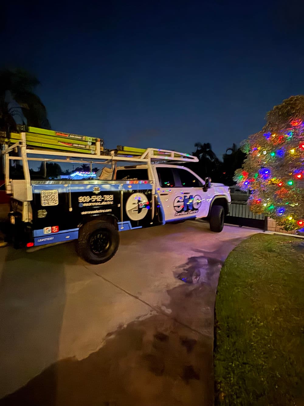 Service truck parked at night, decorated with colorful holiday lights.